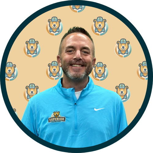 Smiling man in a light blue polo shirt with a 'Superior Comfort' badge, in front of a beige background with bear logos.