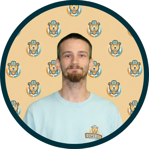 Portrait of a man with short beard wearing a light blue shirt, standing in front of a beige backdrop covered with small bear mascot logos.