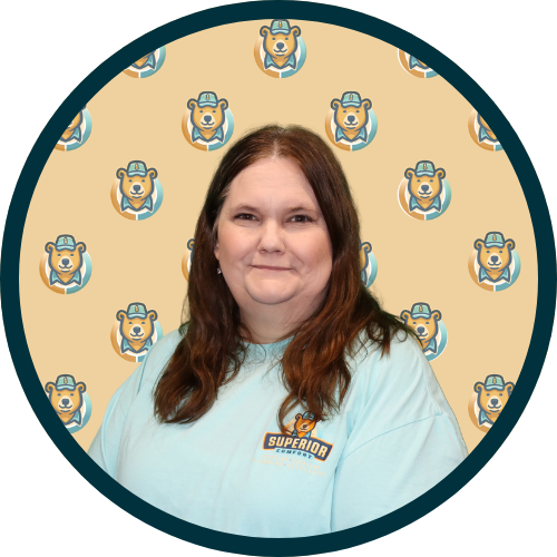 Smiling woman with long brown hair wearing a light blue shirt with a Superior logo, portrait framed by a circular teal border against a bear-patterned beige background.