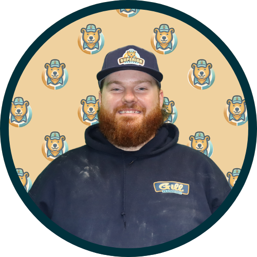 Portrait of a bearded man in a navy hoodie and cap with a grill logo, circular frame with a beige bear mascot pattern background.