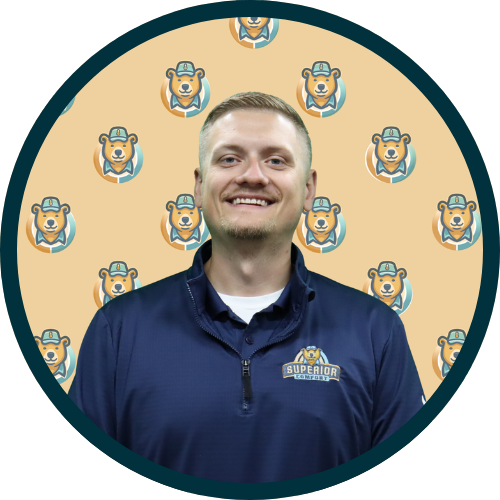 Smiling man in a navy polo with a Superior logo, inside a circular teal frame with a bear-patterned beige background.