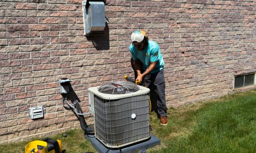 Superior Comfort technician using a pressure gauge on an old AC unit