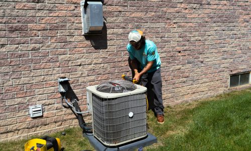 Superior Comfort technician using a pressure gauge on an old AC unit